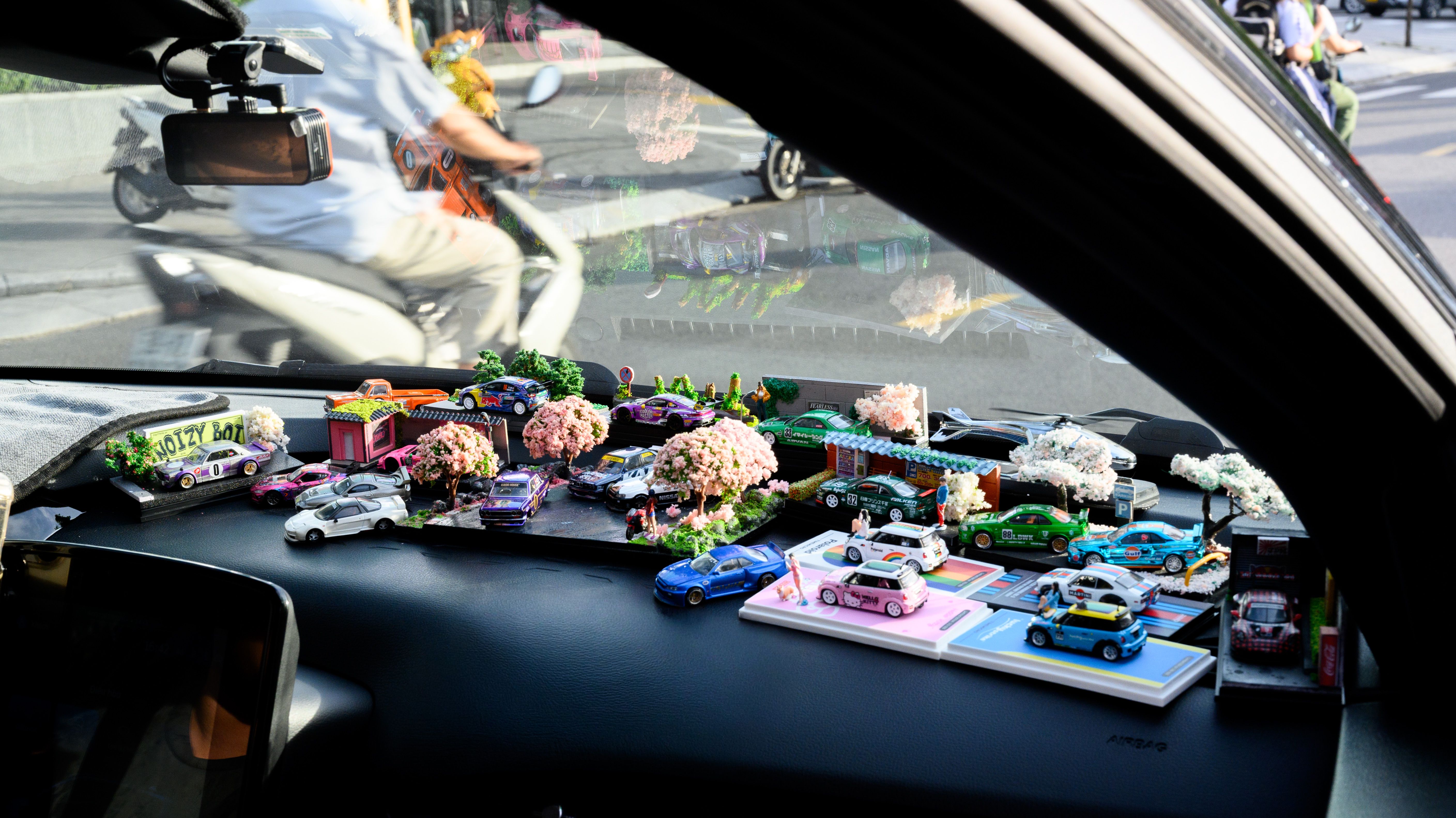 Colorful toy car collection displayed on car dashboard in Ho Chi Minh City.