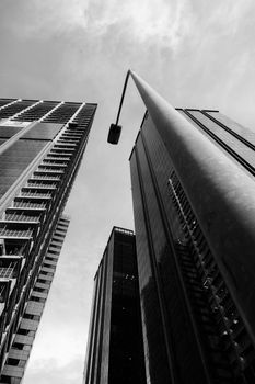 Black and white cityscape showcasing skyscrapers and a towering streetlight against the sky.