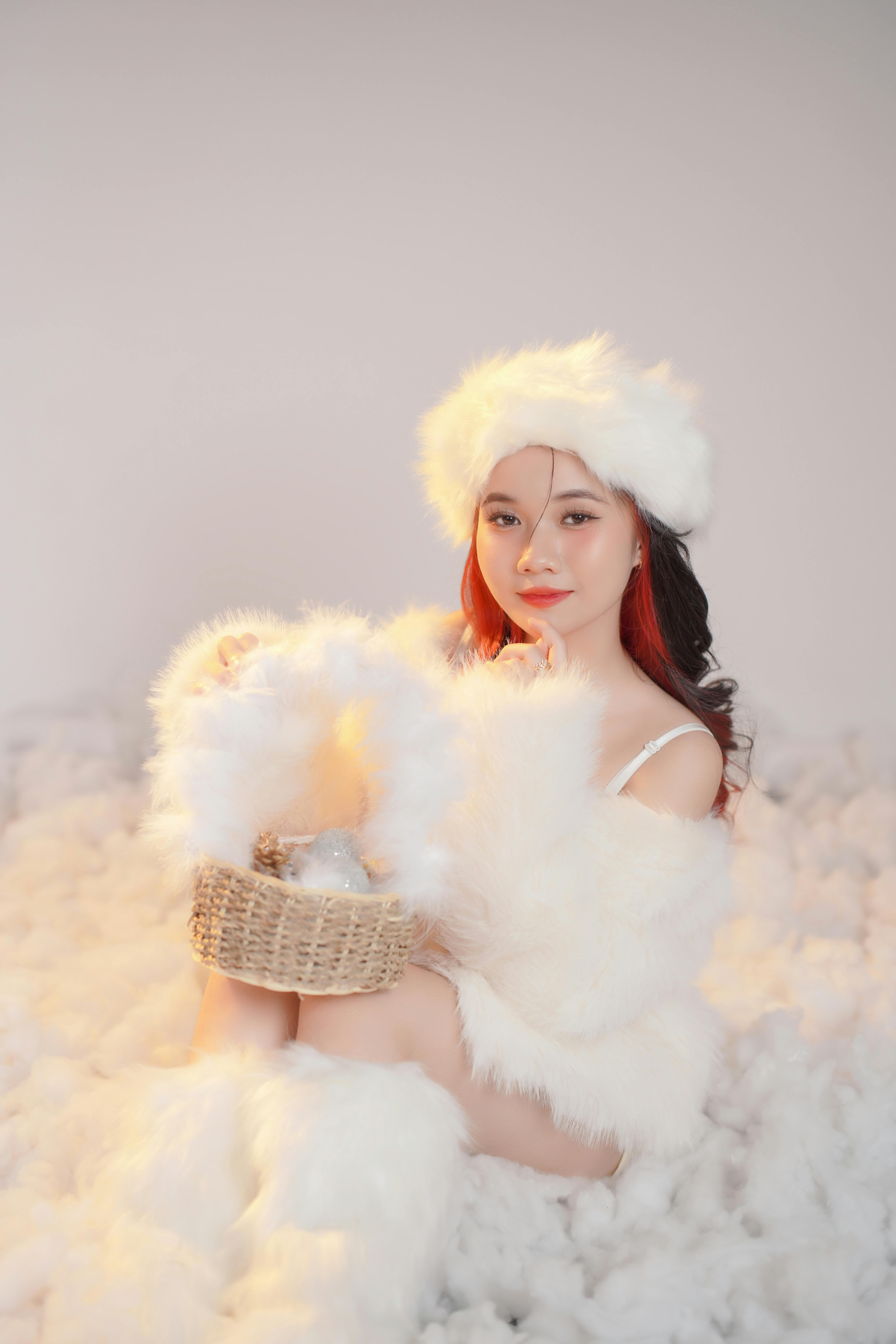 Stylish woman in winter attire holding furry basket in soft lighting.