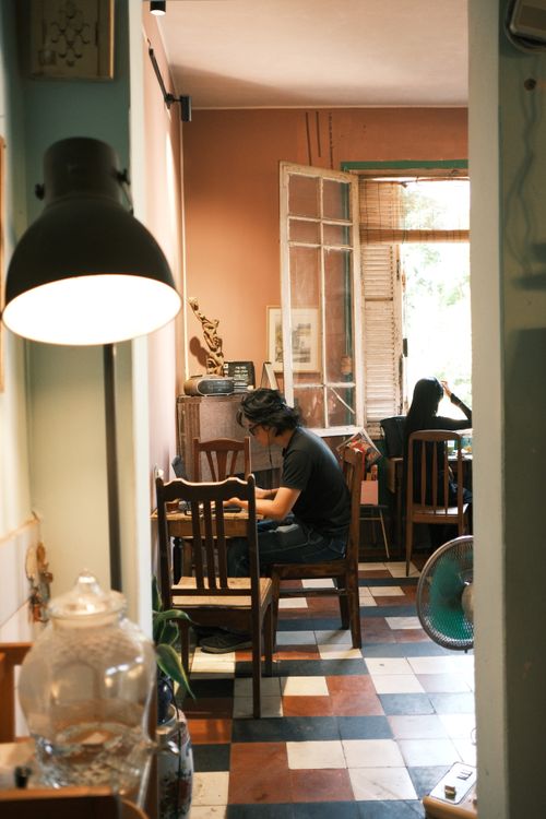 Free A warm, inviting cafe interior with people working and relaxing, featuring natural lighting. Stock Photo