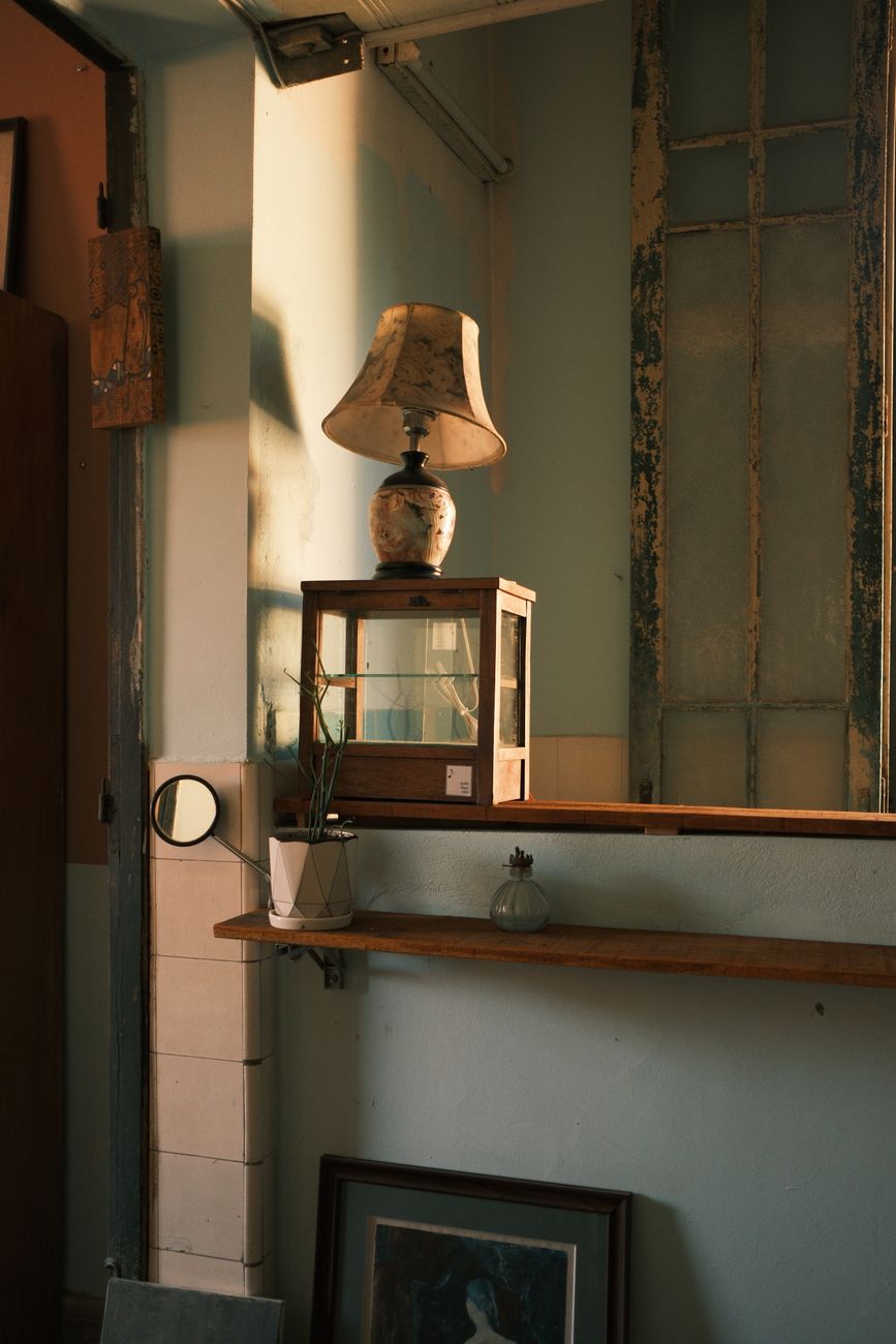 A cozy vintage-style corner in Jamaica with a lamp, potted plant, and artwork, creating a warm and nostalgic atmosphere.