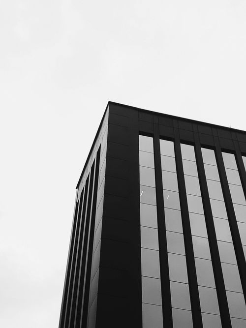 Free Black and white photo of a modern high-rise building with geometric lines and glass facade. Stock Photo