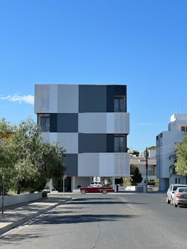 Contemporary architecture with a retro red car on an urban street.