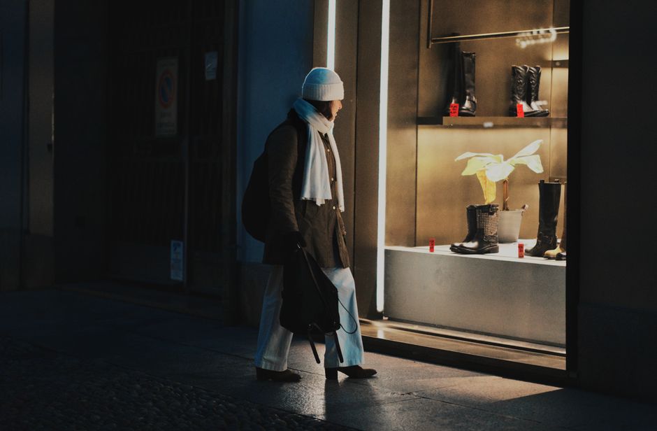 A person window shops at a boutique in Milano, Italy, during a cool night.
