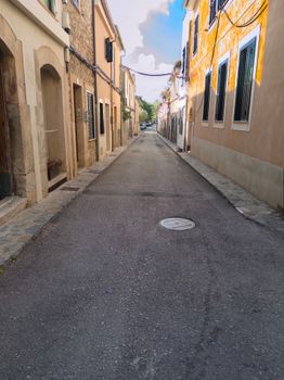 Picturesque narrow street lined with rustic buildings under a bright sky in a historic town.