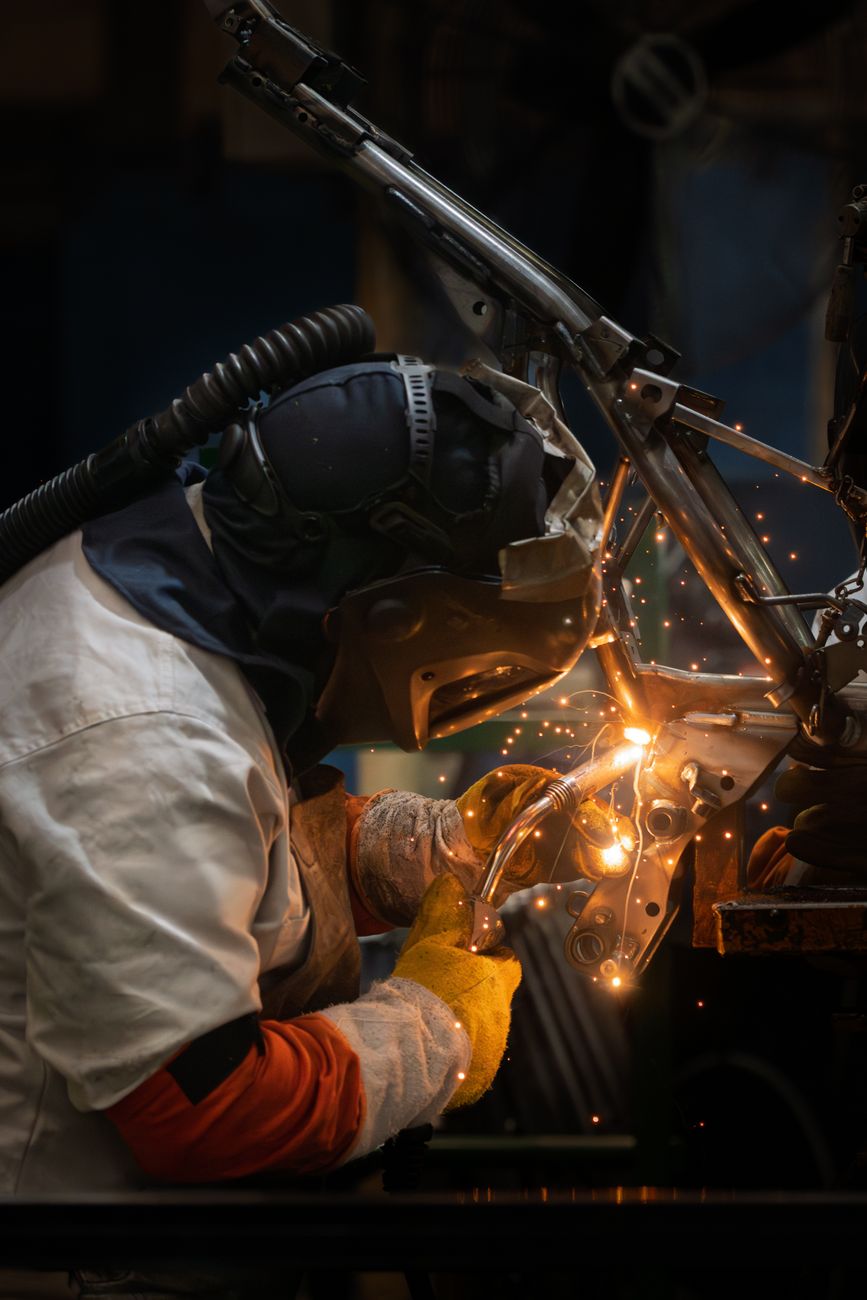 Professional welder performing precision welding in an industrial setting with sparks flying, showcasing craftsmanship.