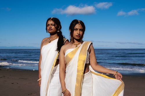 Free Two South Asian women in traditional sarees and accessories posing elegantly on a Vancouver beach during the day. Stock Photo