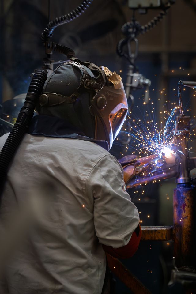Worker in protective gear creating sparks in an industrial setting