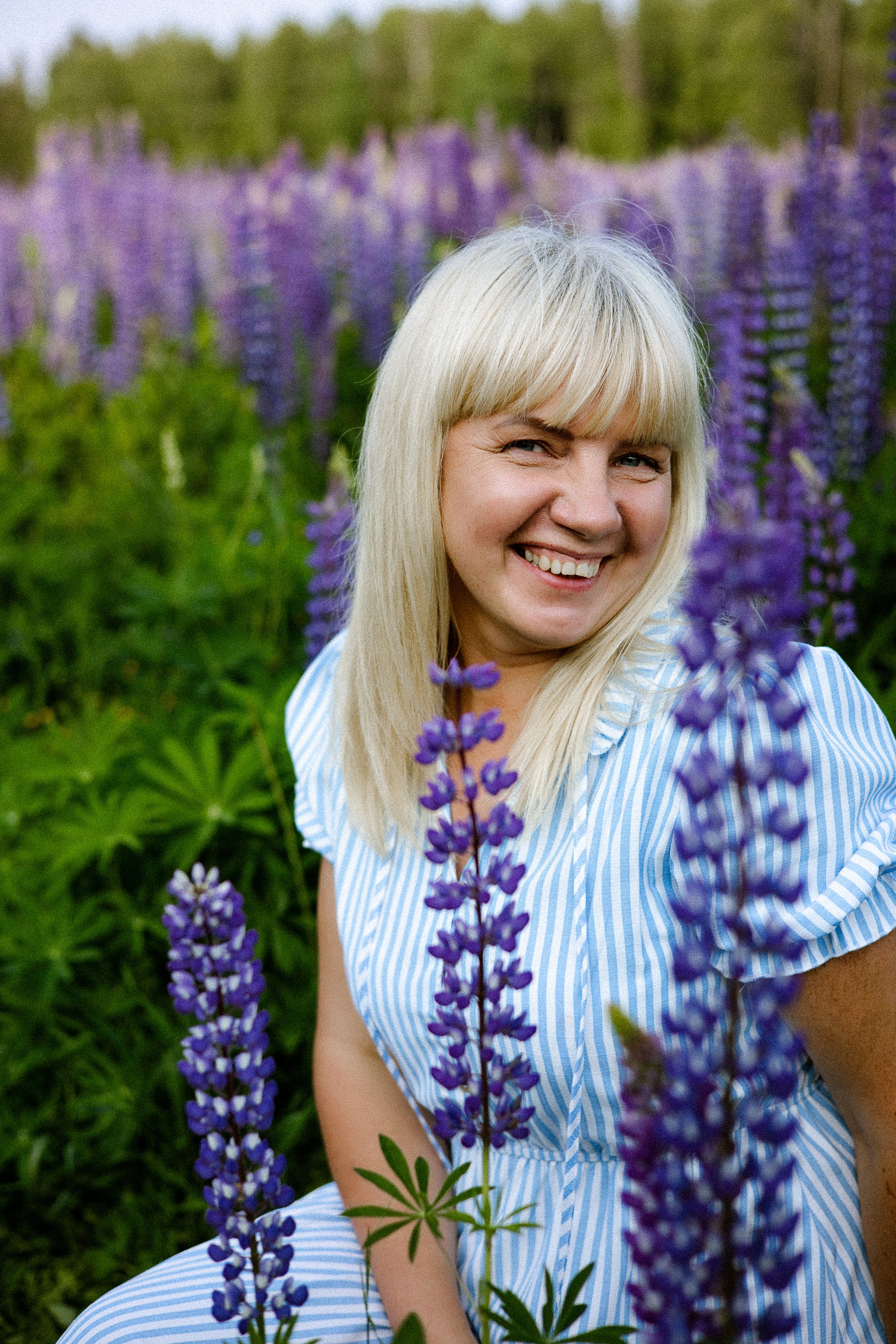 Happy woman enjoying a sunny day in a vibrant lupine field, surrounded by nature's beauty.