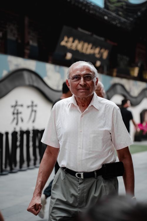 Free A senior man walking through a traditional Chinese street, portraying cultural exploration. Stock Photo