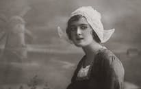 复古的棕褐色肖像，一位穿着传统服装的妇女，背景是风车