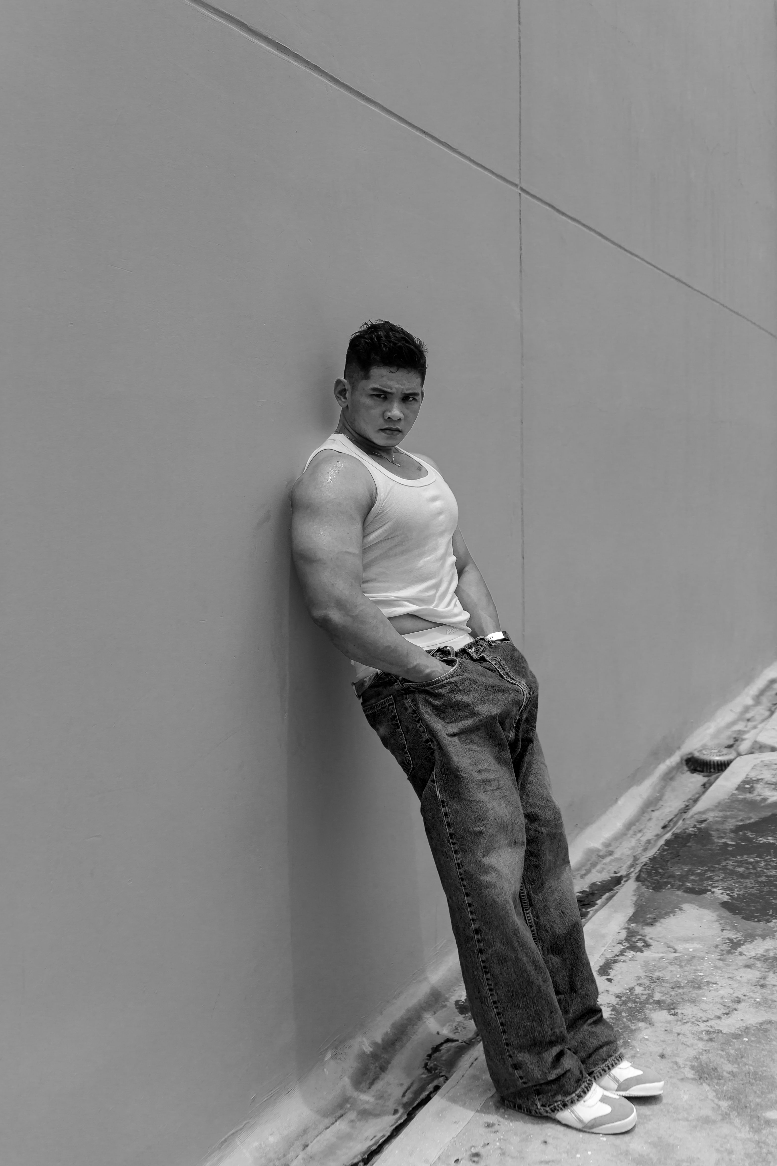Black and white photo of a man in urban setting, casual fashion pose.