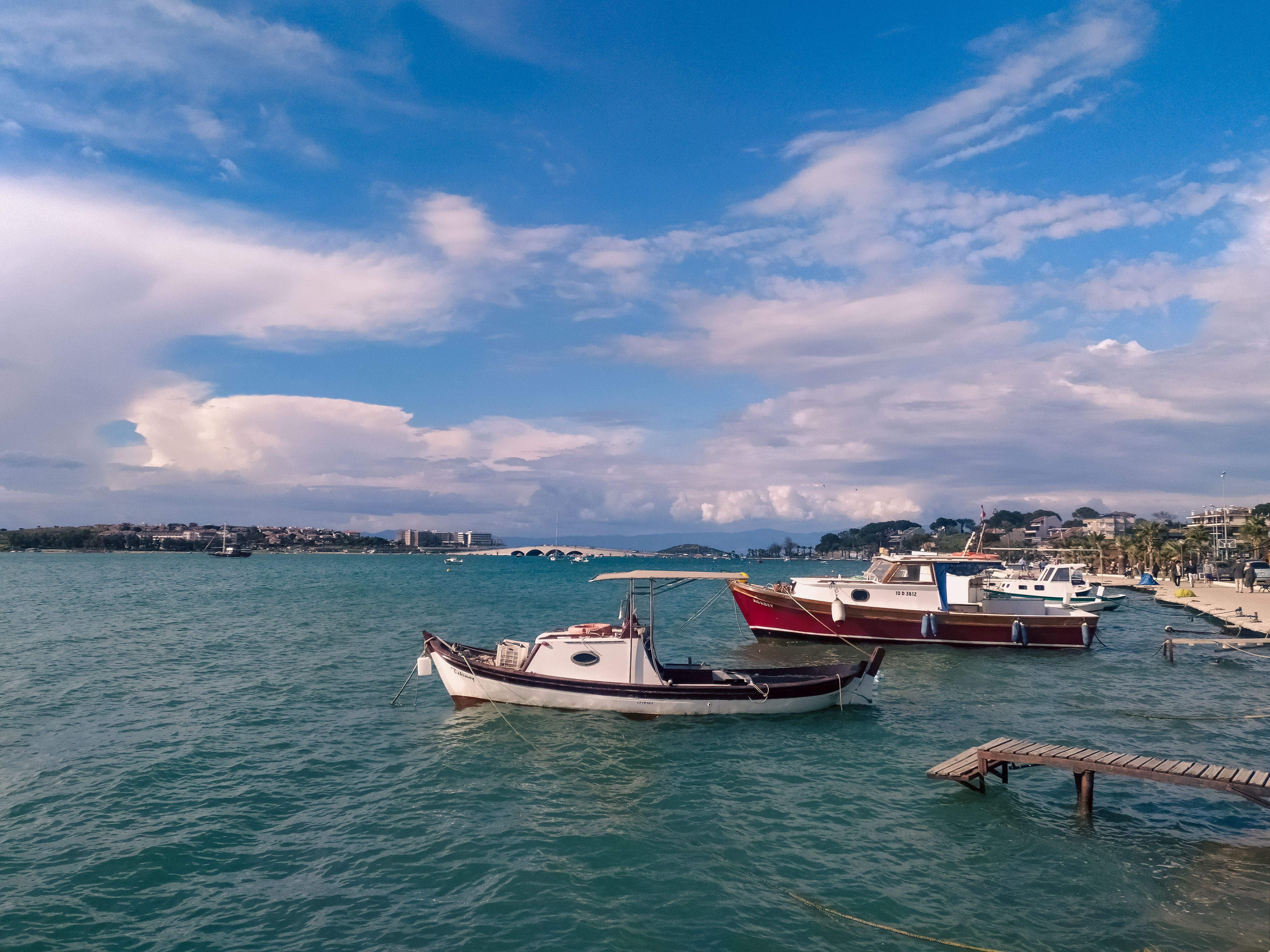 Picturesque boats docked in Ayvalık harbor under a vibrant blue sky, showcasing coastal beauty.