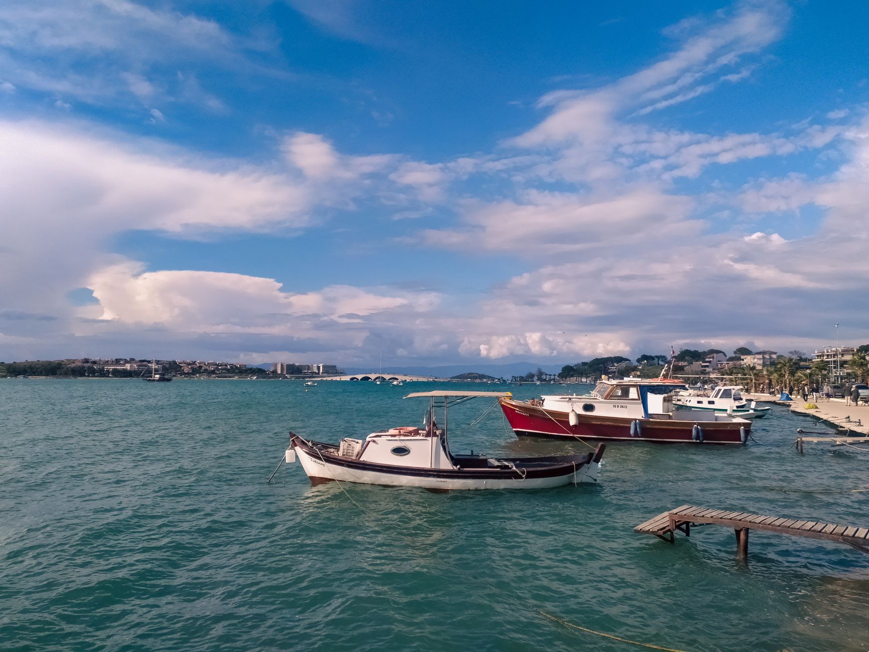 Picturesque boats docked in Ayvalık harbor under a vibrant blue sky, showcasing coastal beauty.