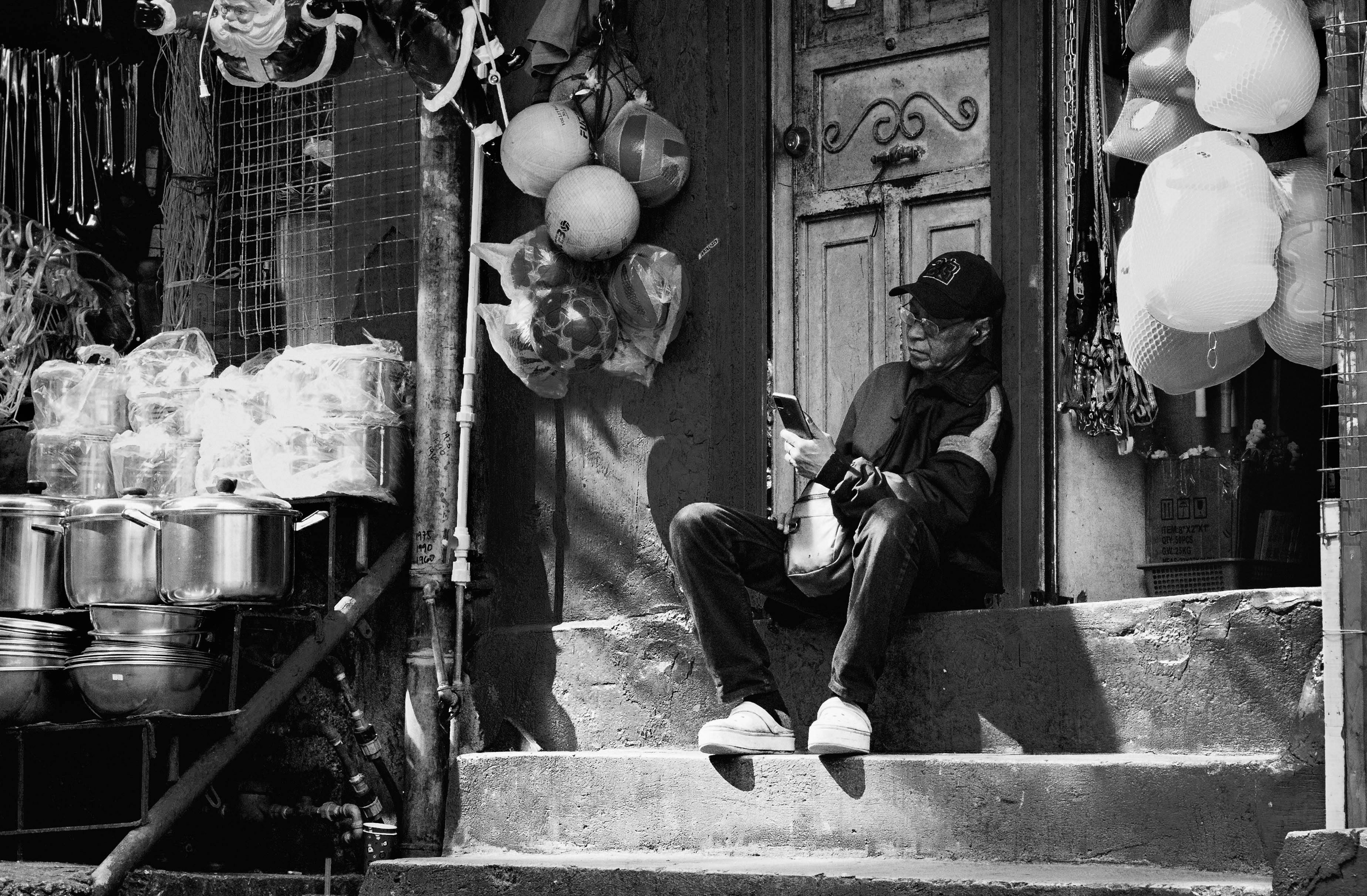 Gratuit Une scène en noir et blanc d'un vendeur de rue se relaxant sur le marché animé de la ville de Baguio. Photos