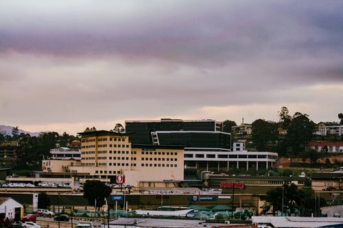 Free View of the Mbabane city skyline featuring commercial buildings and cloudy sky during dusk in Eswatini. Stock Photo