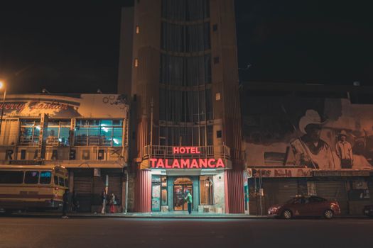 Urban night view of Hotel Talamanca with neon lights, street activity, and striking murals.
