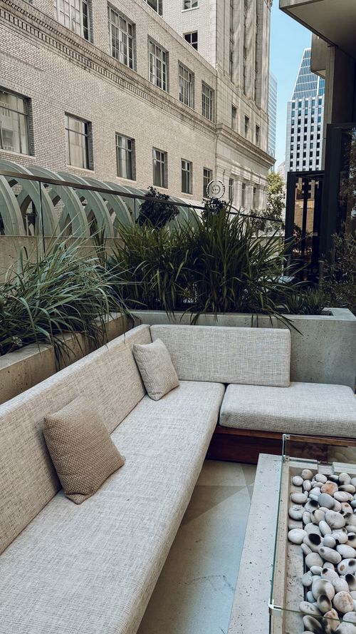 Free Chic urban rooftop terrace with modern seating and lush plants, set against cityscape backdrop. Stock Photo