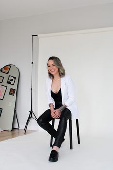 Confident woman in black and white attire posing indoors for a studio portrait.