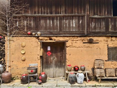 Rustic Asian earth house exterior with clay pots and bamboo baskets showcasing traditional style.
