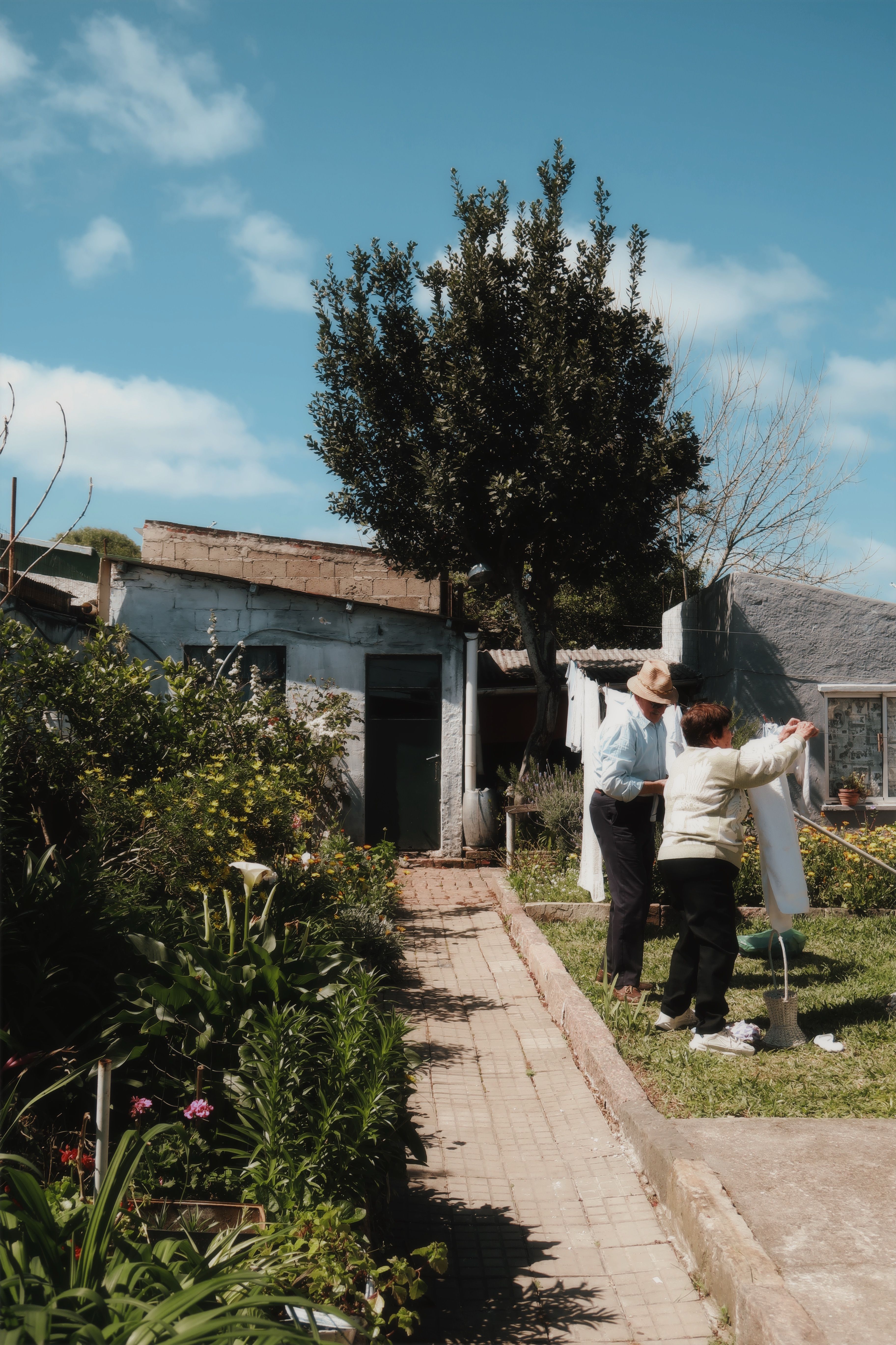 Two people hanging laundry on a sunny day in Melo, Uruguay garden.