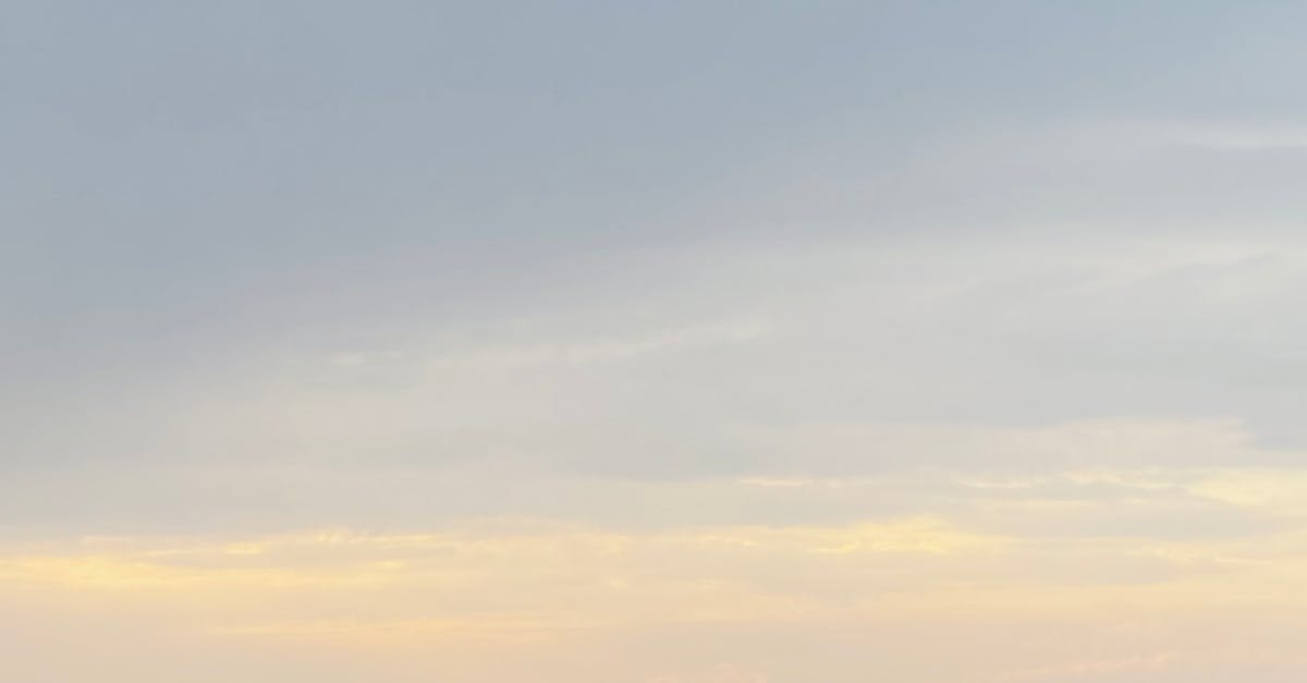Tranquil scene of a rocky coastline and calm sea under a cloudy sky during sunset.