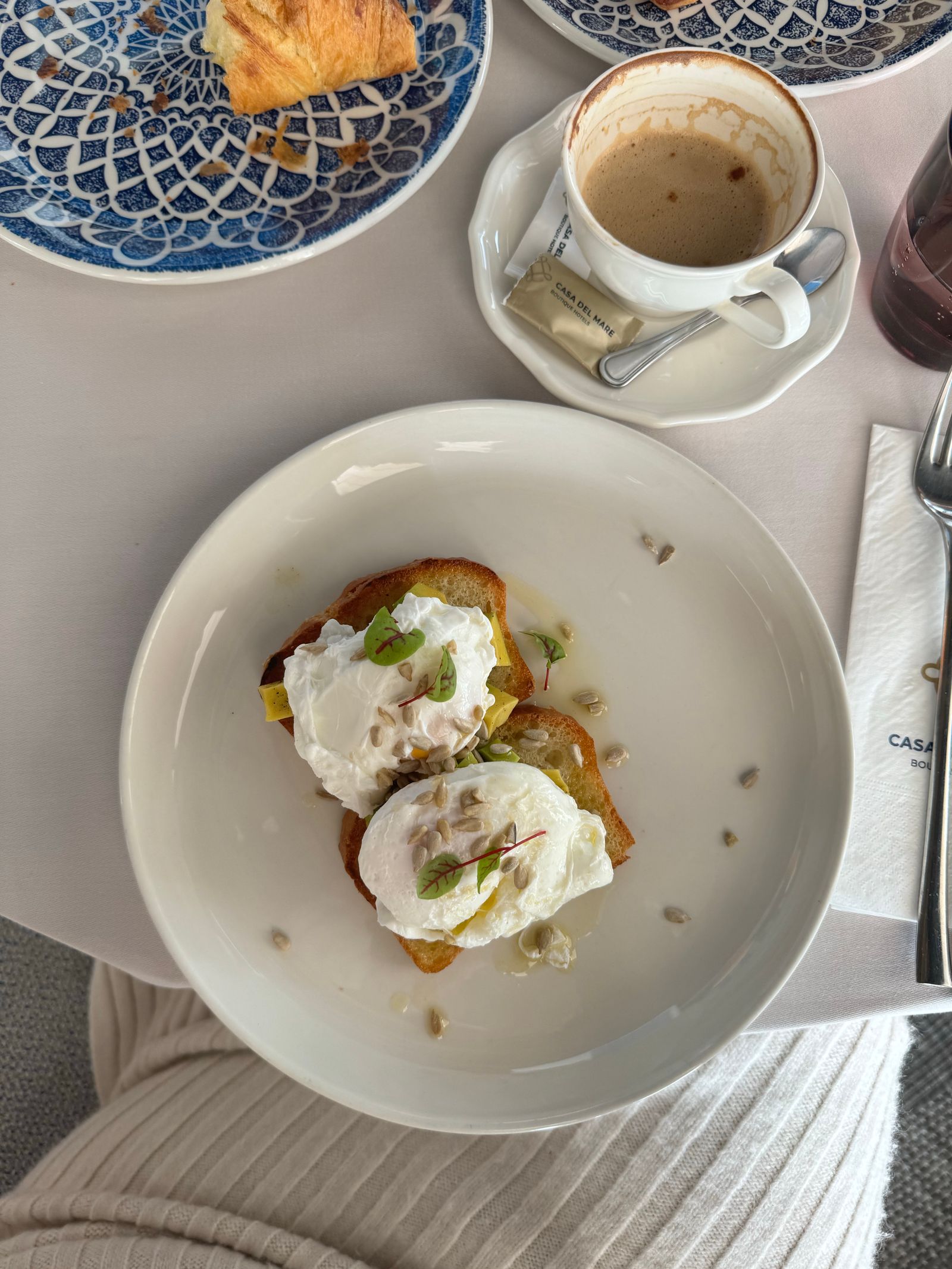 A brunch spread of poached eggs on toast with coffee on a marble table