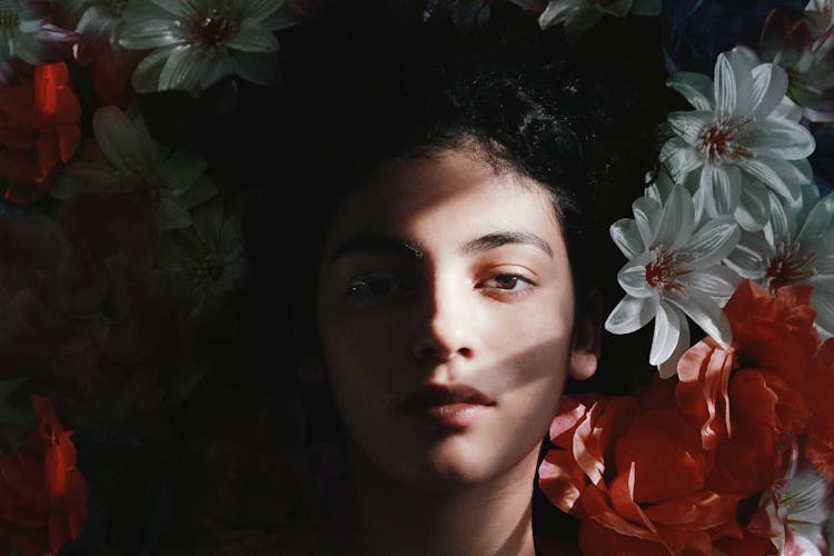 Selective Focus Photography Of Woman Lying On Flowers