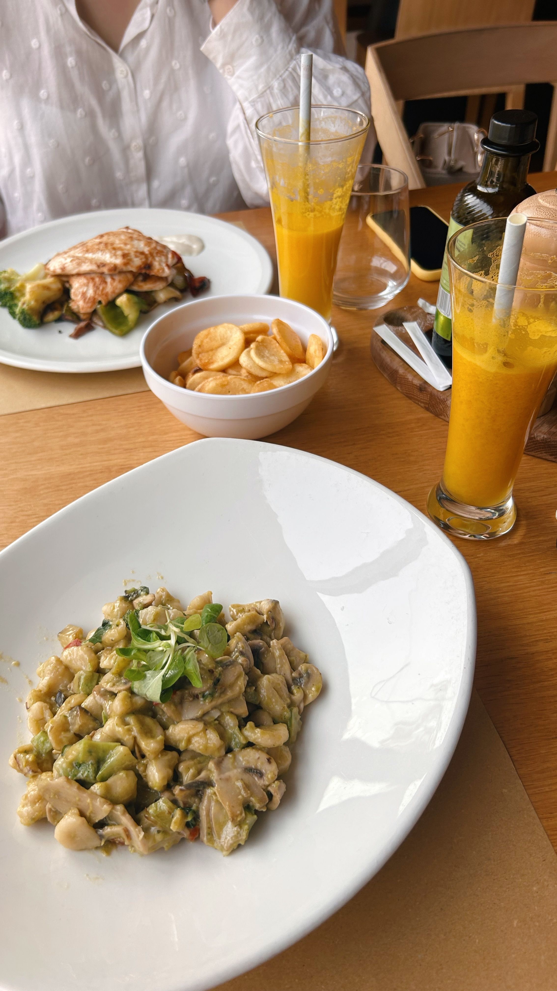 Appetizing pasta dish with drinks on a wooden table, perfect for casual dining.