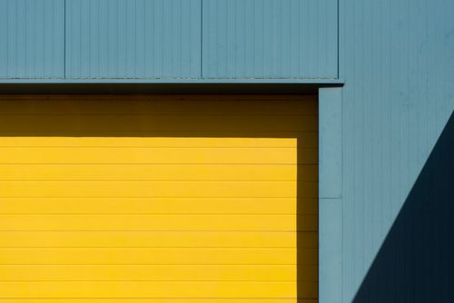 Free Minimalist architecture with a vibrant yellow door and blue wall, highlighting geometric shapes. Stock Photo