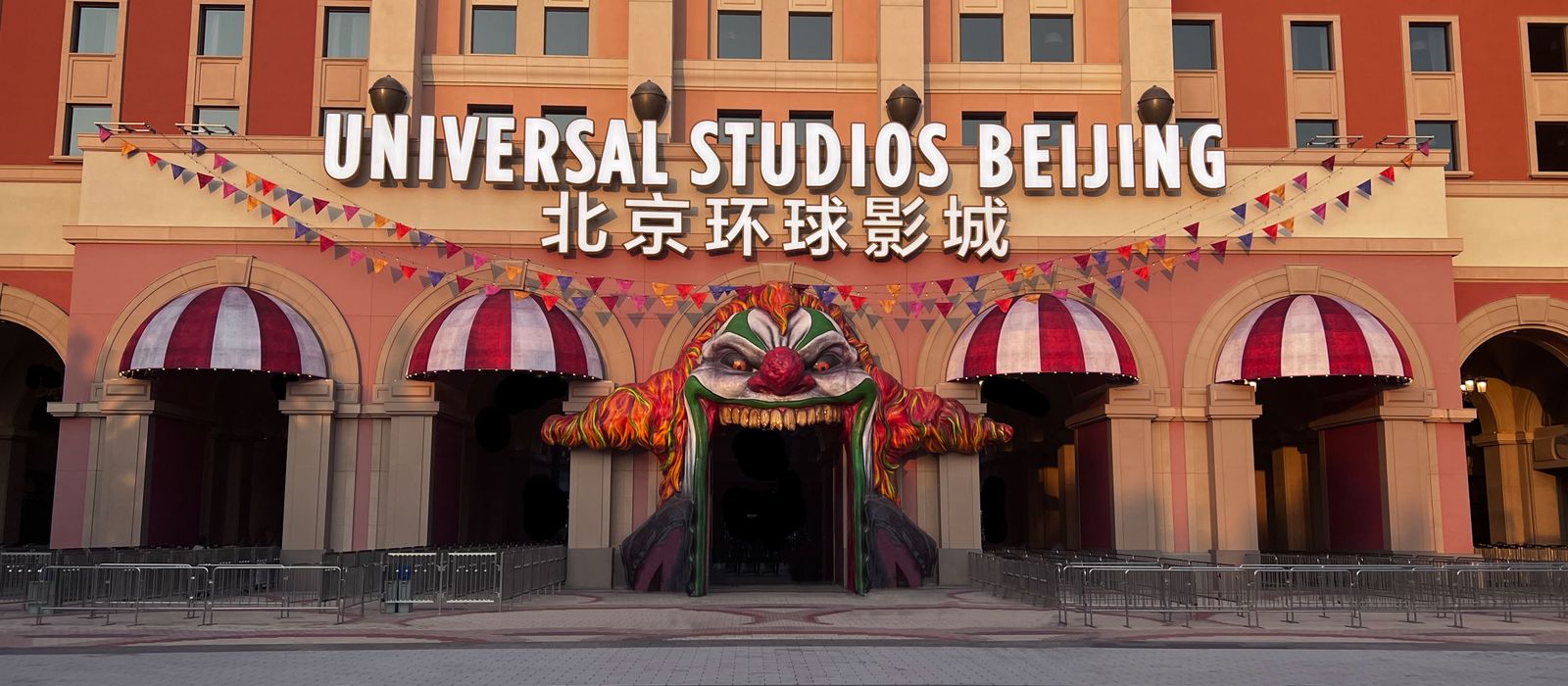 Entrance to Universal Studios Beijing with vibrant clown-themed decor and festive flags.