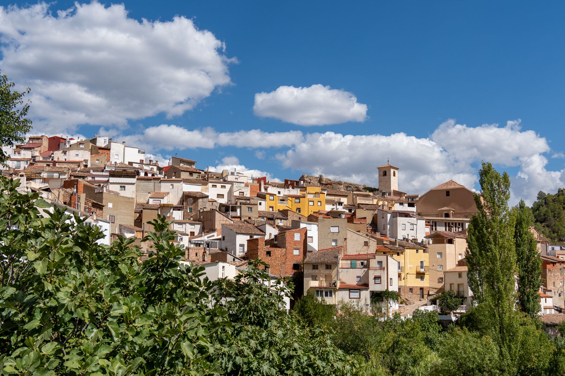 Colorful hillside view of Bogarra, Castilla-La Mancha, under a clear blue sky.