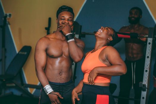 Joyful moment of friends laughing during a workout session in a Ghana gym.