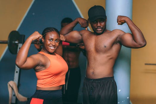 Two adults showcasing their muscles in a gym setting in Accra, Ghana.