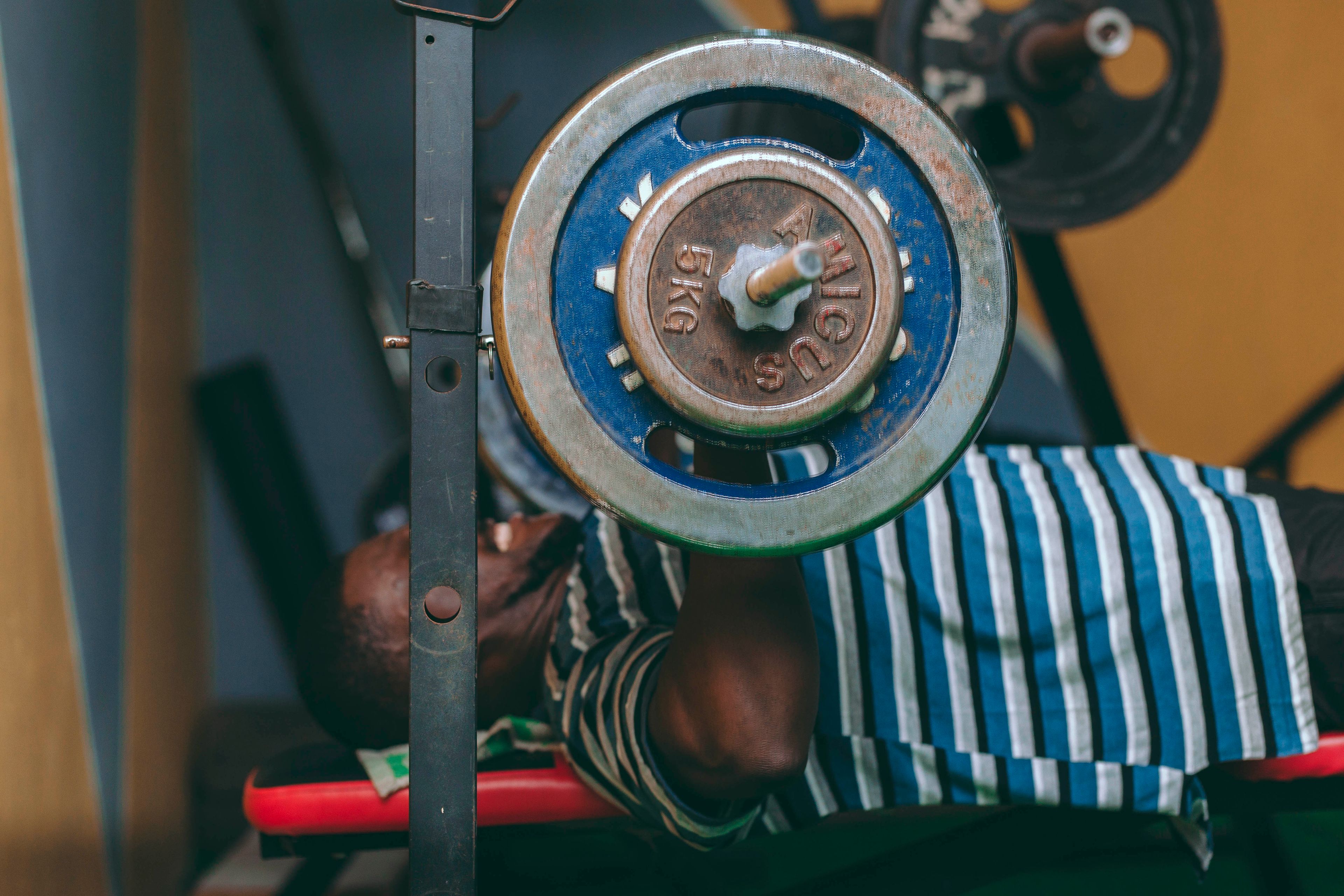 A man lifting weights with a barbell in an indoor gym setting, focused on fitness and strength training.