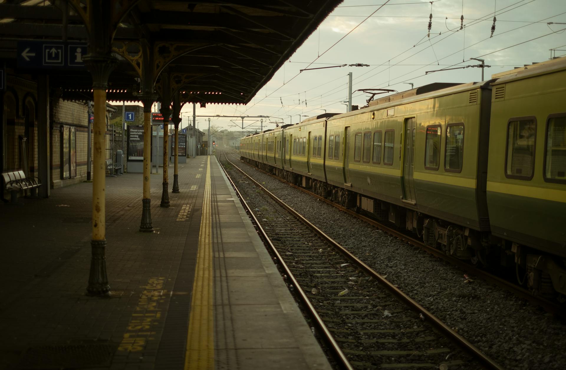 A tranquil morning view of an empty train station in Dublin with a vintage green train parked.