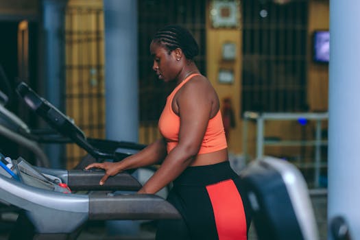 Focused woman working out on a treadmill, maintaining fitness indoors.