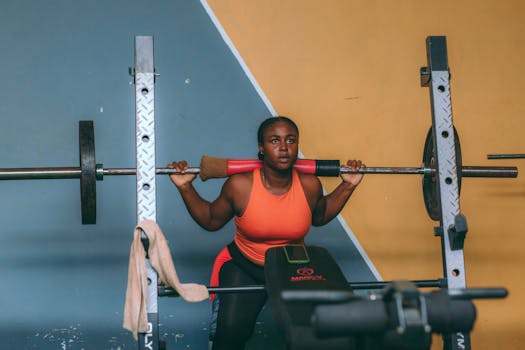 Focused woman lifting weights indoors at a gym in Accra, Ghana.
