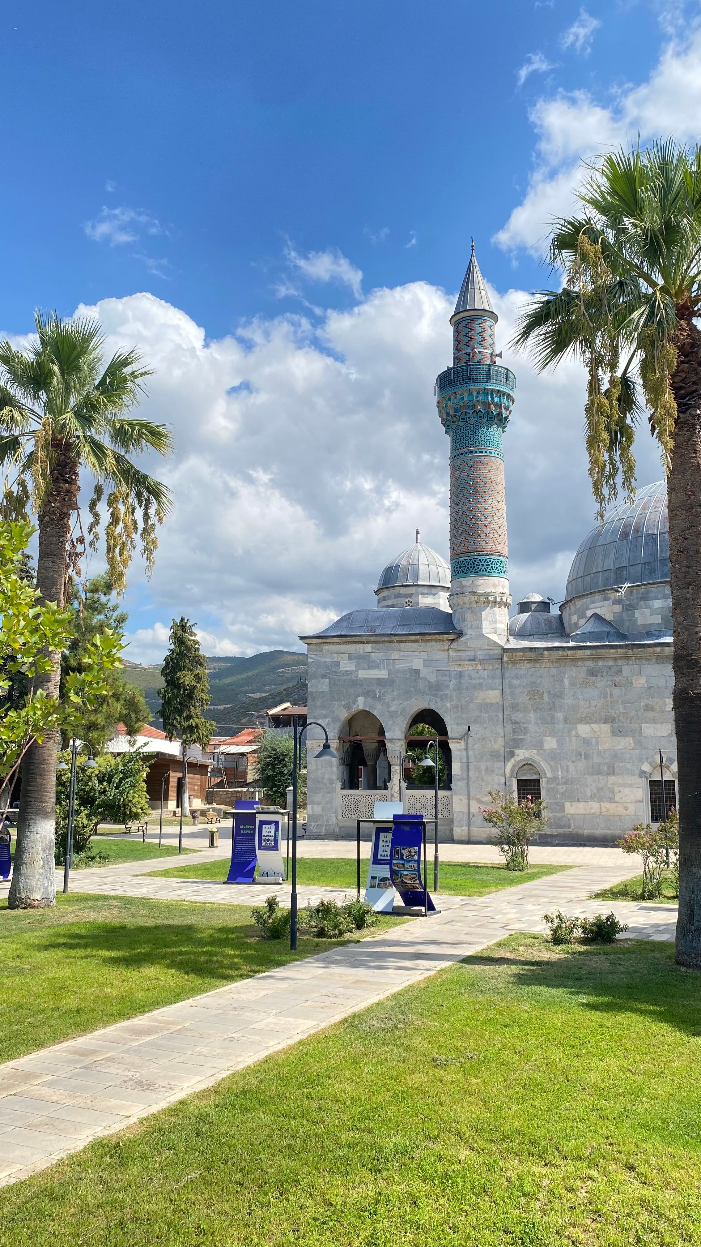 Stunning view of a mosque with minaret surrounded by palm trees under a clear blue sky.