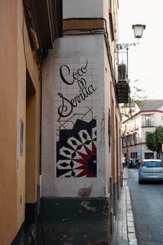 Street corner in Seville featuring decorative ceramic art and sign.