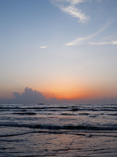 Free Calm ocean waves and vibrant sunset creating a serene seascape. Stock Photo