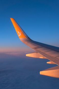 Scenic view of airplane wing with golden sunset above the clouds, showcasing aviation beauty.