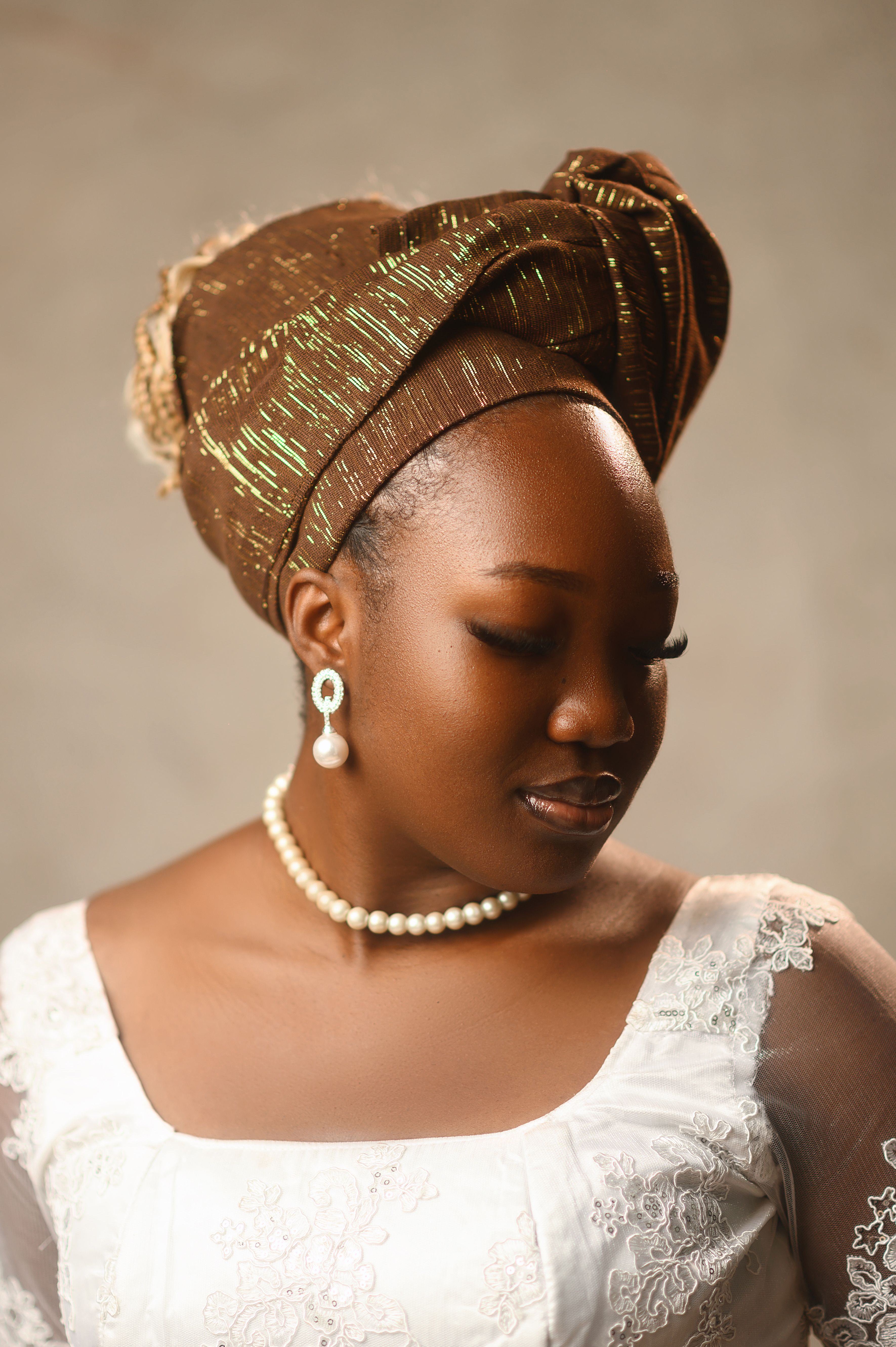 Elegant portrait of a woman in traditional attire with pearls and a stylish headwrap.