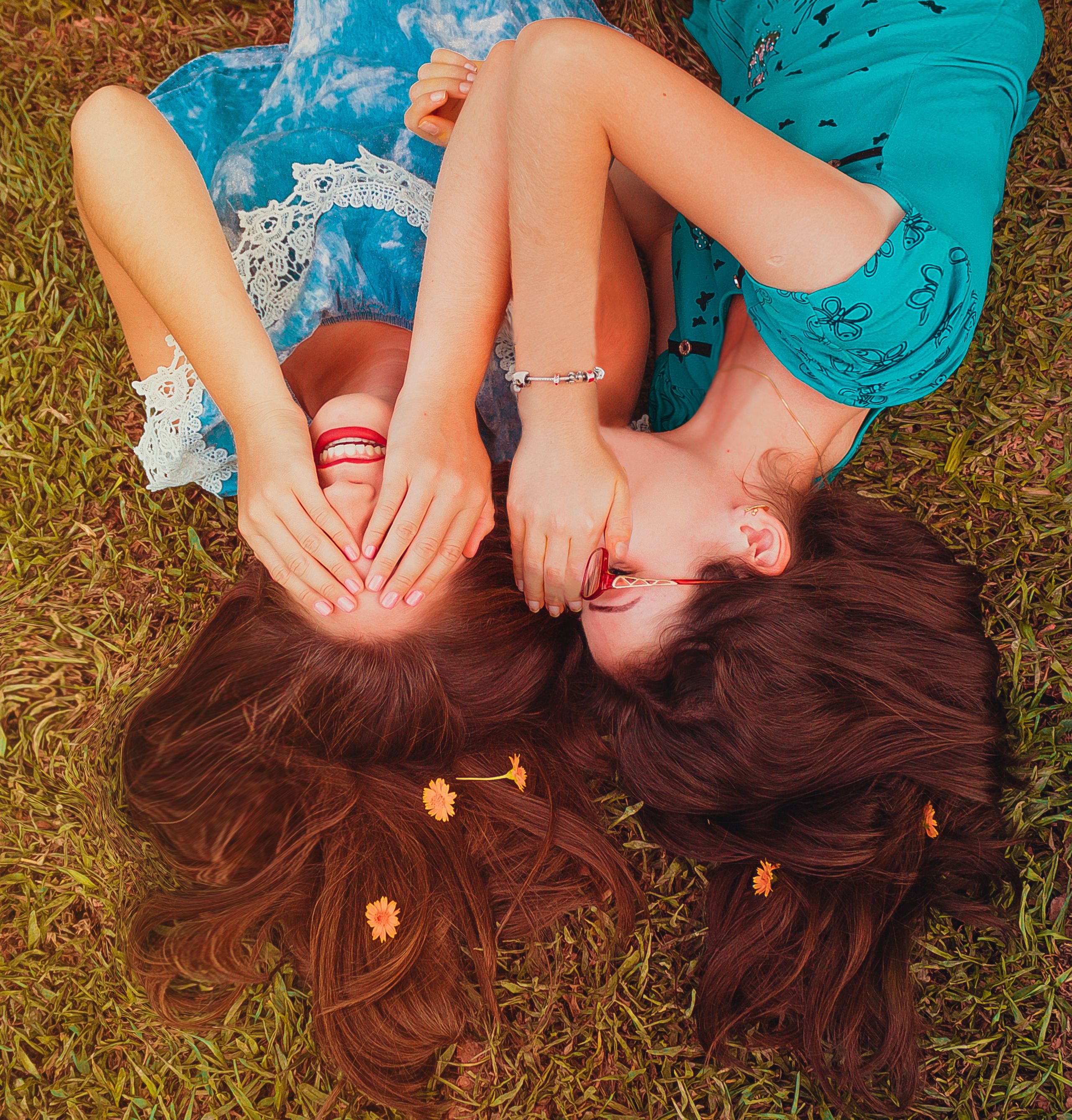 Two Women Wearing Blue Shirt Lying on Grass