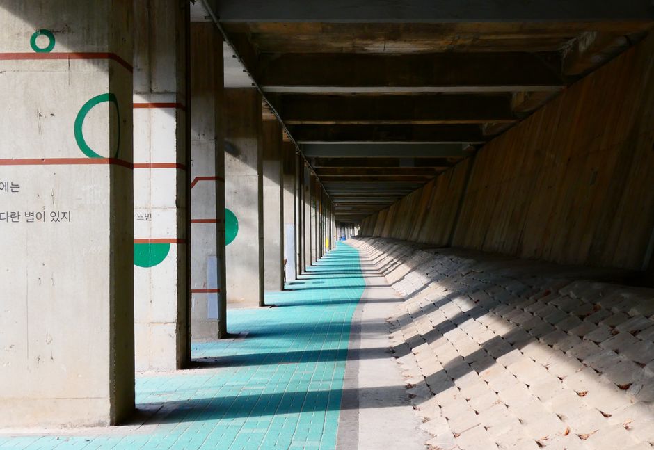 Concrete underpass featuring geometric wall art with angular shadows on a sunny day.