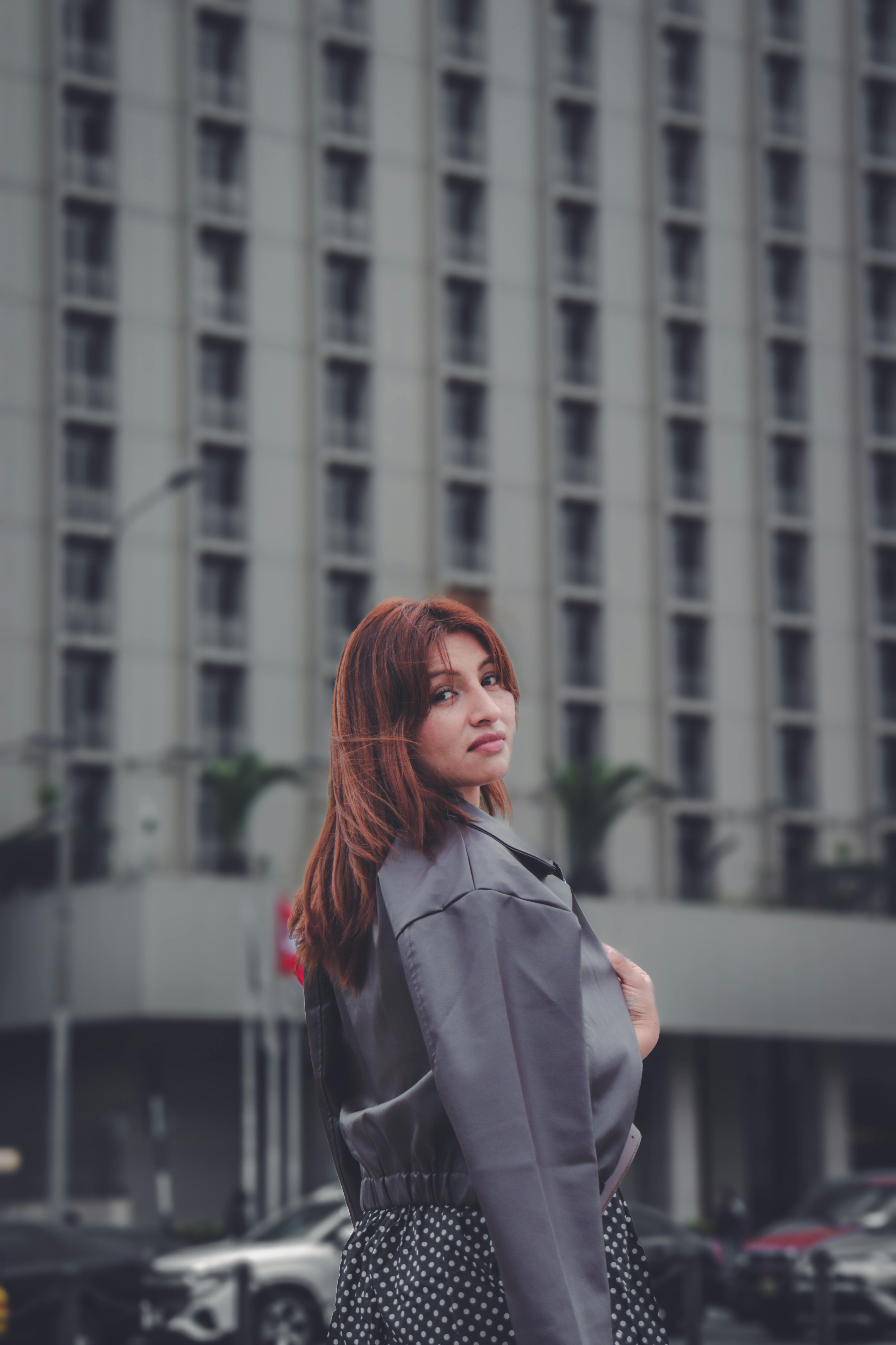 Stylish urban portrait of a woman in fashionable attire with a city building backdrop.