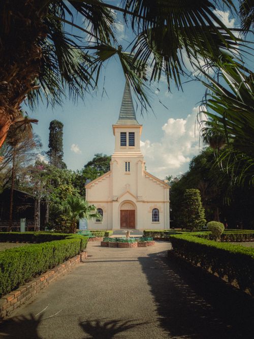 Free A picturesque church surrounded by vibrant gardens under a clear blue sky. Stock Photo