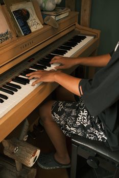A teenager plays a Yamaha piano in a cozy room, reflecting a relaxed lifestyle.