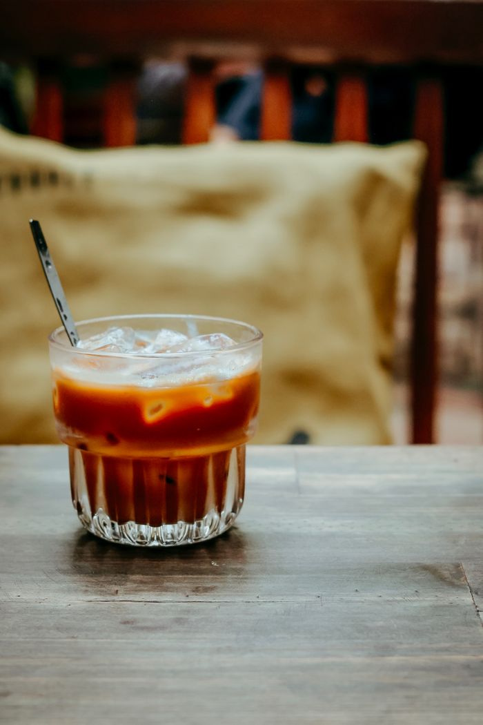 Iced coffee in a ribbed glass on a worn table — photo by Nguyễn Tiến Thịnh on Pexels
