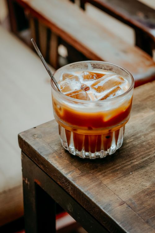 Free A refreshing iced coffee with cream served in a glass with ice on a rustic wooden table. Stock Photo